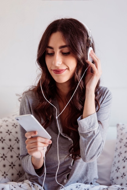 Foto gratuita morena con teléfono inteligente disfrutando de la música