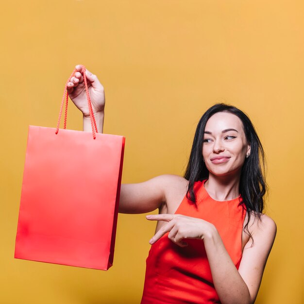 Morenita sonriente que muestra el bolso de compras