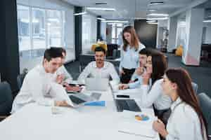 Foto gratuita mostrando buenos resultados. grupo de jóvenes autónomos en la oficina conversando y sonriendo