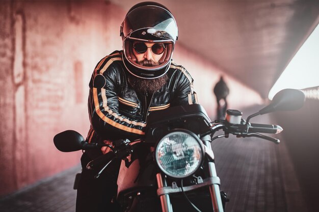 Motociclista barbudo brutal en casco y chaqueta de cuero está listo para ir.