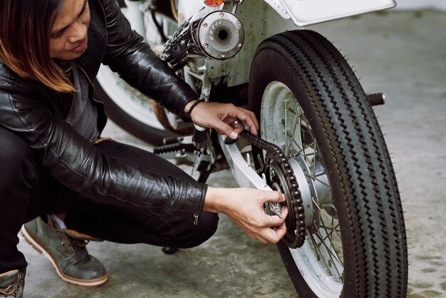 Motorista asiático arreglando su motocicleta antes de un paseo