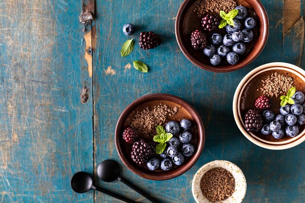 Mousse de chocolate con arándanos y moras y menta fresca en moldes sobre una mesa de madera azul