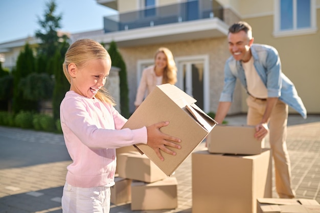 Moviente. Linda familia desembalaje de cajas de cartón mientras se muda a una nueva casa