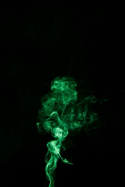 Movimiento de humo de giro verde brillante sobre fondo negro con espacio de copia para escribir el texto