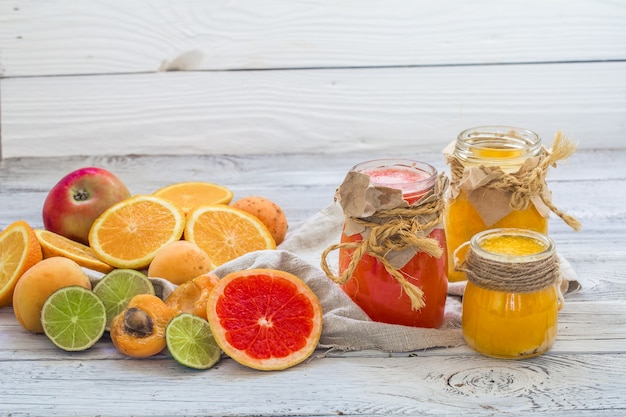 Mucha fruta fresca, cortada en un hermoso fondo de madera, bebida de fruta fresca, mermelada, comida sabrosa y saludable