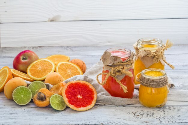 Mucha fruta fresca, cortada en un hermoso fondo de madera, bebida de fruta fresca, mermelada, comida sabrosa y saludable