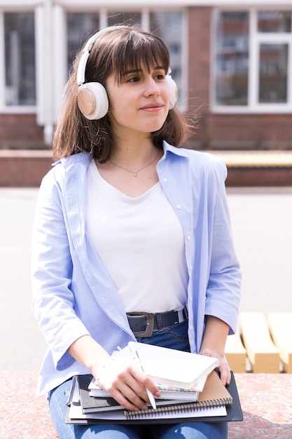 Foto gratuita muchacha del adolescente en los auriculares que se sientan con los libros