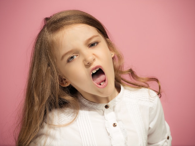 Muchacha adolescente enojada que se coloca en rosa de moda. Retrato femenino de medio cuerpo. Las emociones humanas, el concepto de expresión facial.