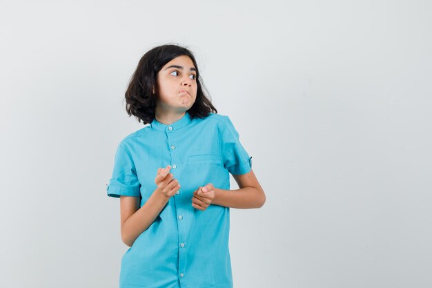 Muchacha adolescente que mira a un lado en camisa azul y que parece emocionada.