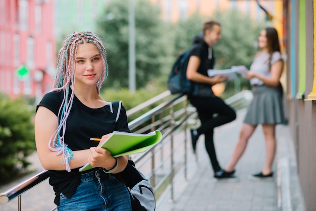 Muchacha adolescente soñadora con el libro de texto