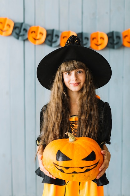 Foto gratuita muchacha adolescente en traje de bruja con calabaza