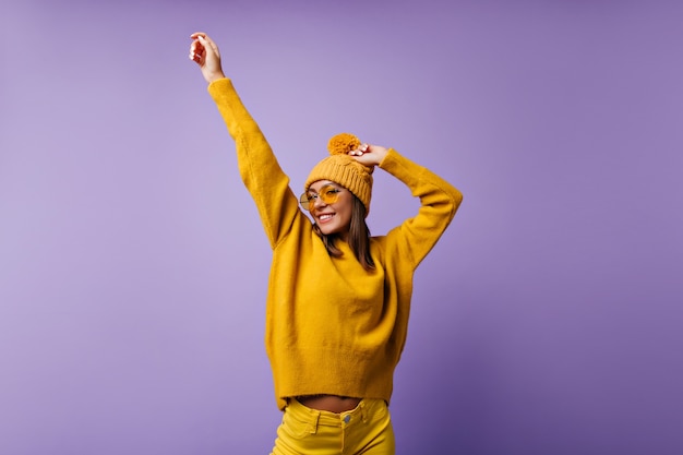 La muchacha adorable alegre mueve sus manos. Retrato de estudiante activo en jeans brillantes