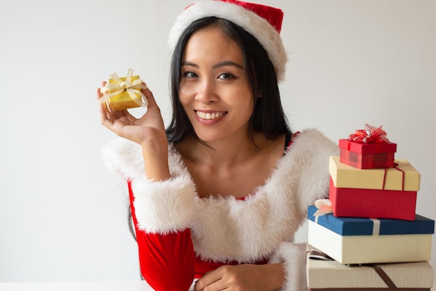 Muchacha alegre de la Navidad que muestra la pequeña caja de regalo