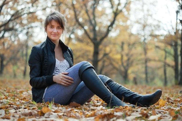 Muchacha en altos zapatos en el parque del otoño