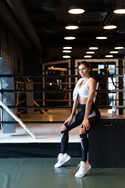 Foto gratuita muchacha apta sonriente que sostiene la toalla y que descansa en gimnasio.