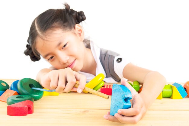 La muchacha asiática preciosa es juguete colorido del bloque de madera del juego