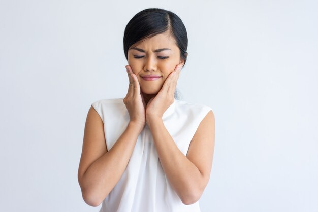 Muchacha asiática sonriente que disfruta del efecto de la crema facial