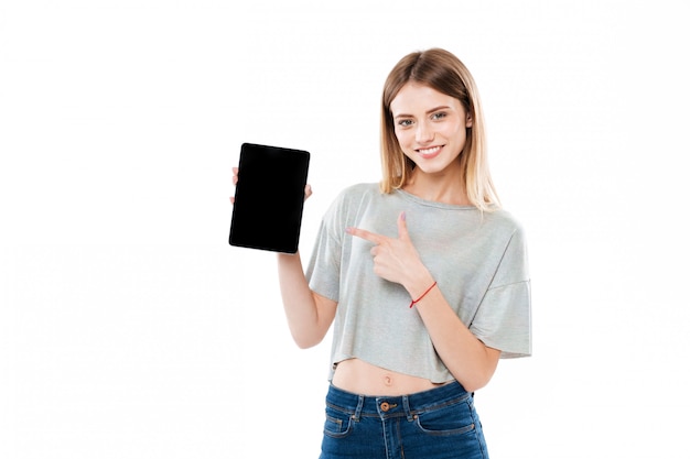 Foto gratuita muchacha atractiva sonriente que señala el dedo en la tableta de la pantalla negra