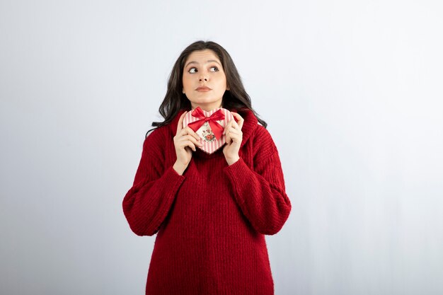 Muchacha de la belleza con la caja de regalo en forma de corazón que mira lejos.