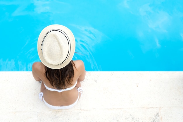 Muchacha bonita que se relaja en la piscina en el verano