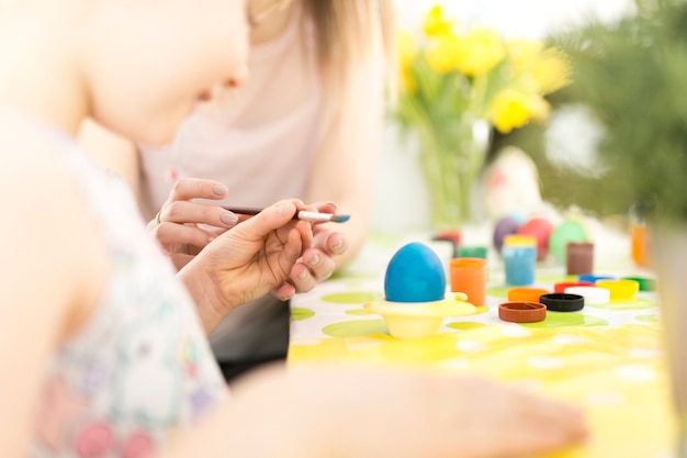 Muchacha de la cosecha y madre que decoran los huevos