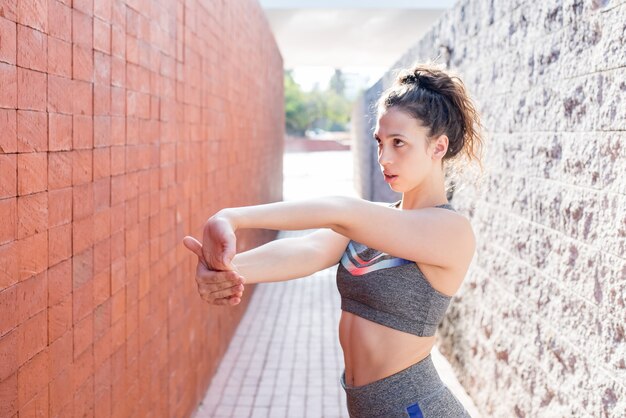 Muchacha deportiva seria que estira los brazos entre las paredes