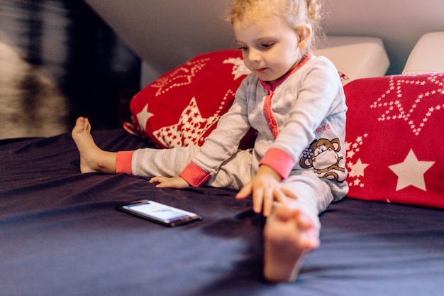 Muchacha divertida viendo video en la cama