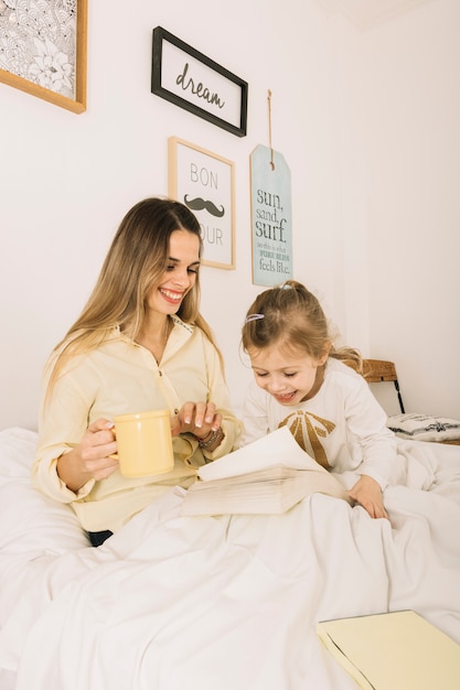 Muchacha encantadora que se divierte cerca de la madre de lectura