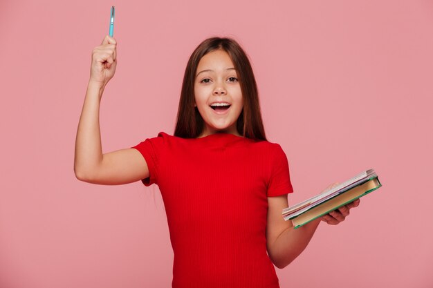 La muchacha feliz con el lápiz y los libros tiene e idea una sonrisa aislada