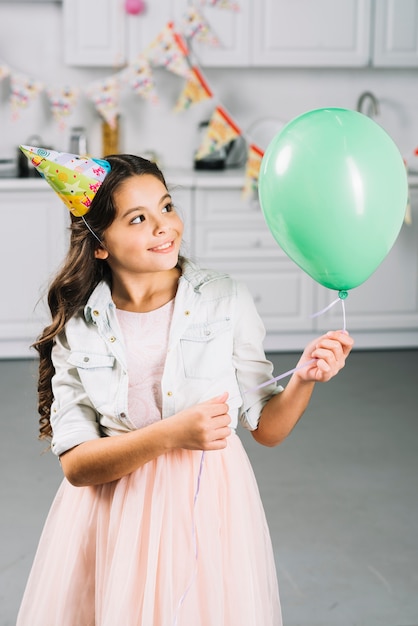 Muchacha feliz que mira el globo verde en cocina