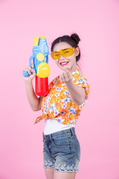 Muchacha feliz que sostiene un arma de agua rosado del fondo.