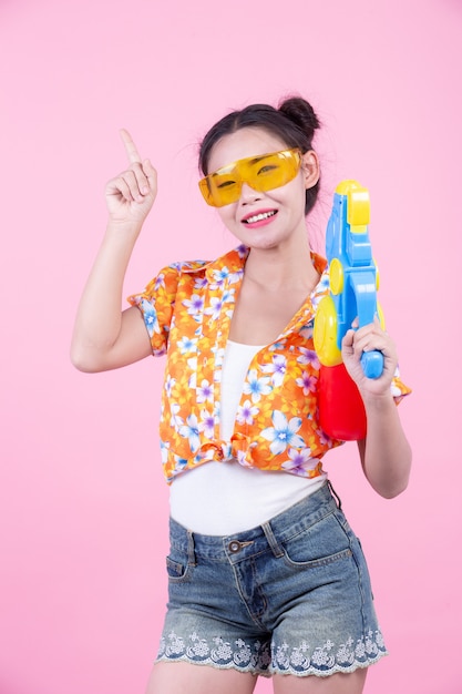 Muchacha feliz que sostiene un arma de agua rosado del fondo.