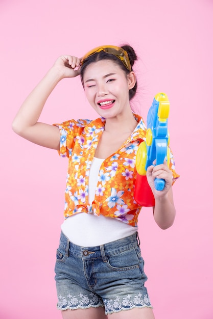 Foto gratuita muchacha feliz que sostiene un arma de agua rosado del fondo.