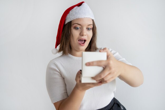 Muchacha gordita sorprendida en la caja de regalo de la apertura del sombrero de santa