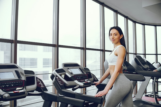 Muchacha hermosa y elegante que se coloca en un gimnasio