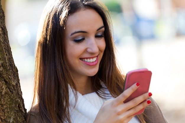 Muchacha hermosa que charla con el teléfono móvil en otoño.