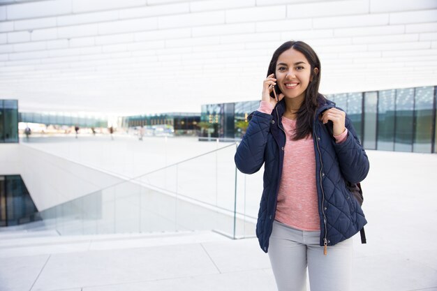 Muchacha india alegre del estudiante que habla en el teléfono móvil