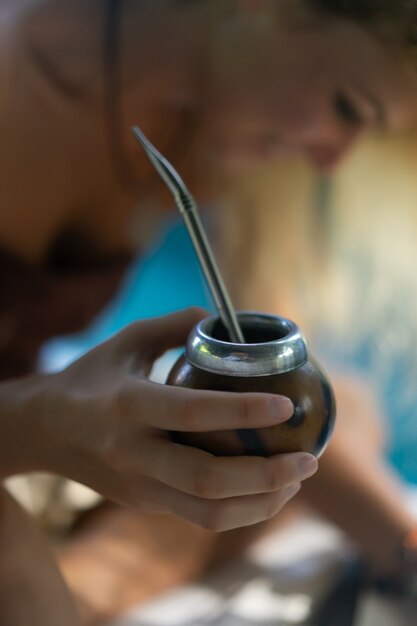 Muchacha india hermosa del hippie con el pelo rubio largo en el té de consumición del compañero del tejado.