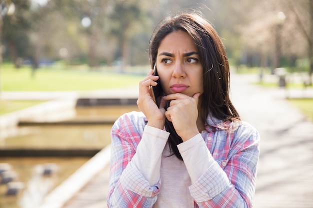 Muchacha infeliz trastornada que discute malas noticias en el teléfono