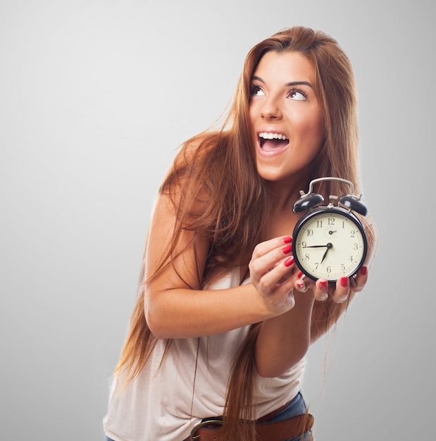 La muchacha linda con el reloj de alarma