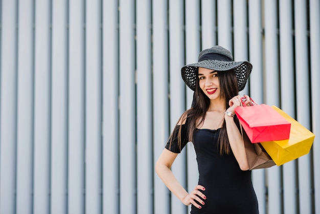 Muchacha de moda que sostiene bolsos de compras que sonríen