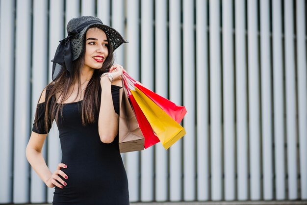 Muchacha de moda que sostiene bolsos de compras que sonríen