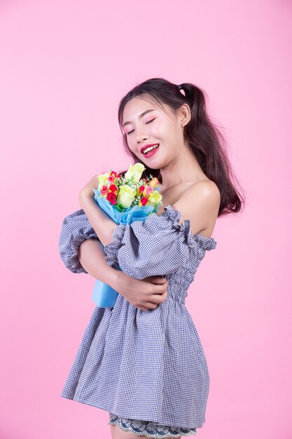 La muchacha de la moda se viste para arriba con gestos de mano en un fondo rosado.