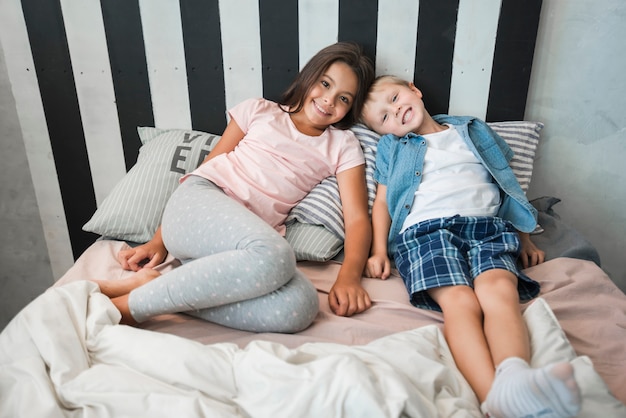 Foto gratuita muchacha y muchacho sonrientes que mienten en cama en casa