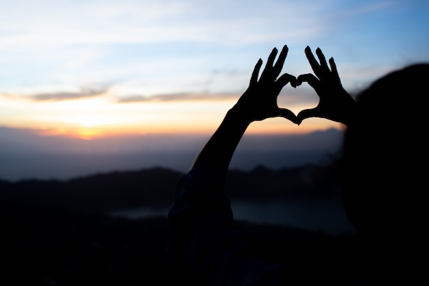 La muchacha muestra el corazón con las manos. sobre el volcán batur. bali. Indonesia