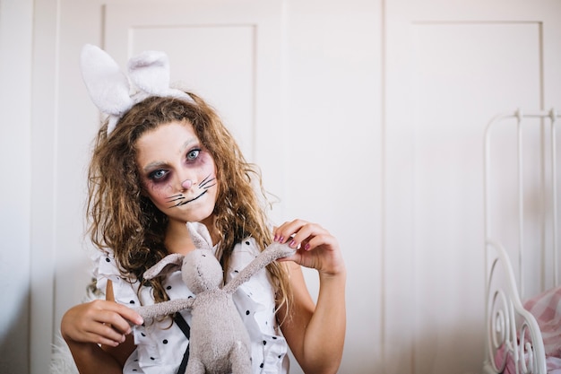 Muchacha con las orejas del conejito y el conejo del juguete