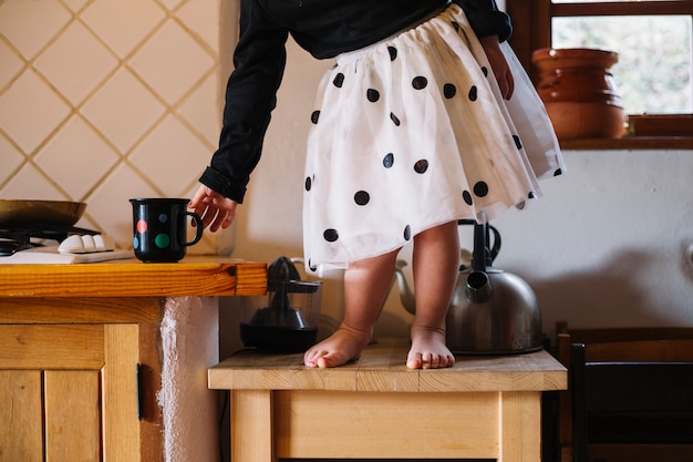 Foto gratuita muchacha que se coloca encima del taburete que sostiene la taza