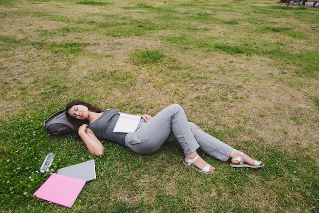 Muchacha que duerme en hierba en parque