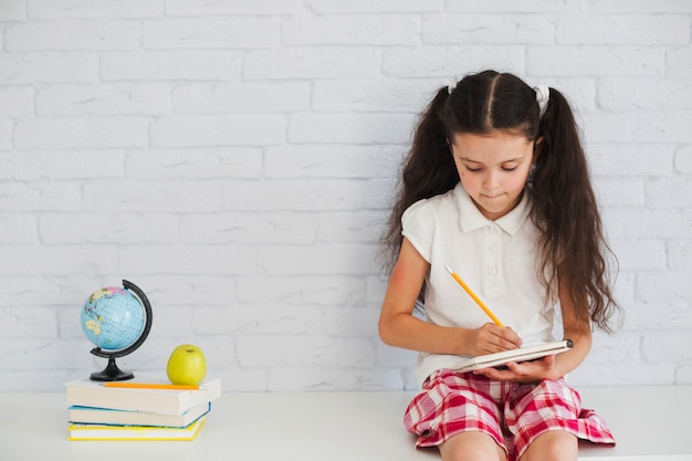 Muchacha que se inclina contra la escritura de la pared