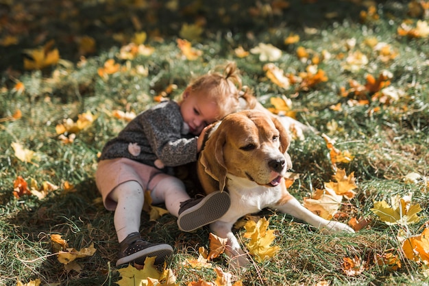 Muchacha que miente en su perro del beagle en el parque